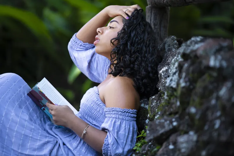 Debutante com um livro, encostada na pedra
