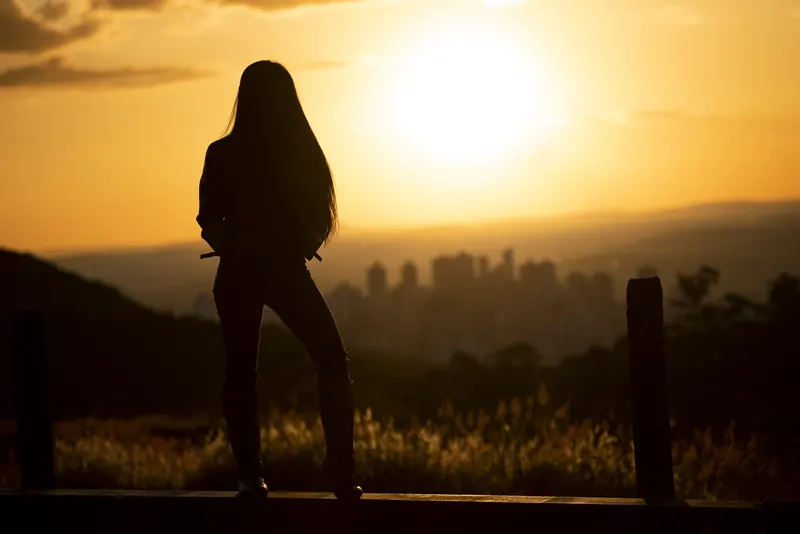 Silhueta diante da cidade ao pôr do sol
